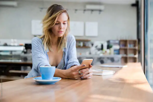 mulher mexendo no celular na cafeteria